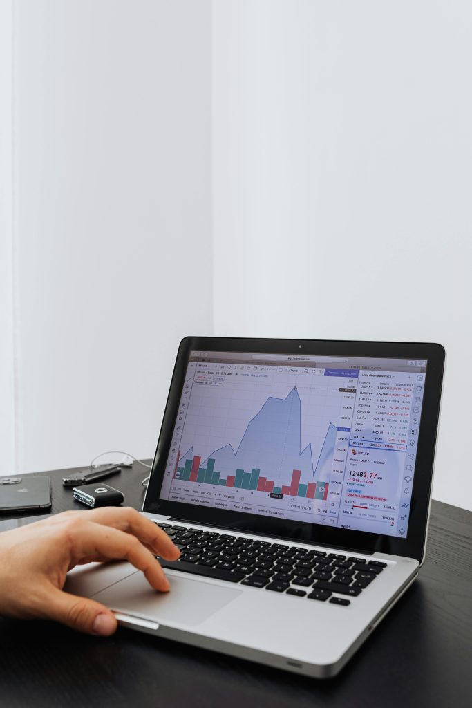 A person analyzing financial data on a laptop with graphs displayed on the screen.